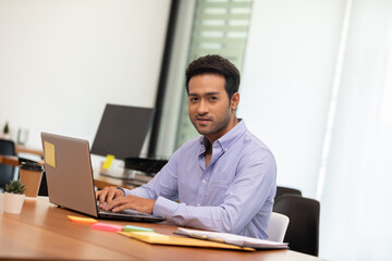 Portrait of Young business indian man working with laptop at office
