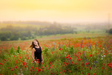Beautiful smiling woman in red poppy field