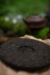 Pressed disk of shu pu-erh tea on craft paper in forest 