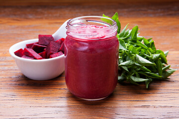 Nutrition concept - Healthy meals in glass jars over wooden background. Canned homemade beetroot in glass jar with fresh organic beetroots and rosemary plant.
