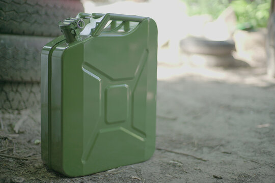 Canister of gasoline. Green Metal military style Jerrycan with Free Space for text on blurred background