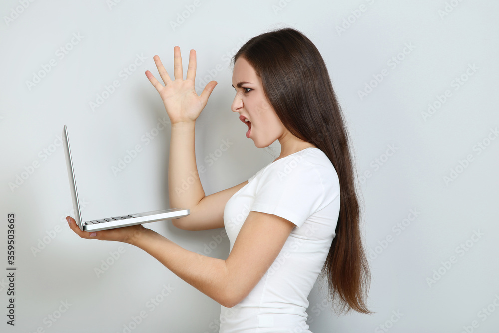 Wall mural Young girl with laptop computer on grey background