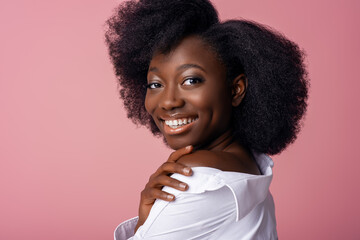 Yong beautiful happy smiling African American woman, model posing in studio, on pink background....