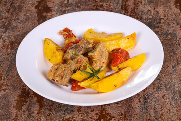 Baked pork meat with potao and tomato