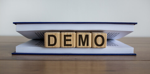 Concept word 'demo' on wooden circles between pages of a book on a beautiful wooden table. White...