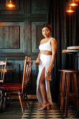 African american woman, retro hairstyle in white dress at restaurant.