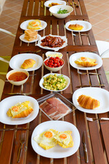 Breakfast is on the table.A large company set the table.Breakfast at the cottage.Croissants with fried eggs, avocado, jamon. Fried bacon with toast for lunch.Lunch for a big company.Food on the table