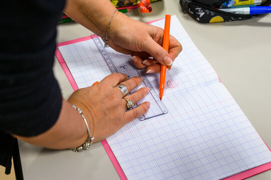L'institutrice indique les consignes sur le cahier de l'&eacute;l&egrave;ve