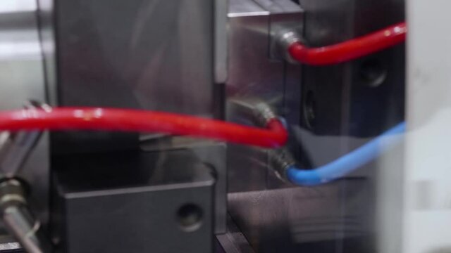 Production of red plastic details in press molding machine. Blurred view of machine and focused view of ready details