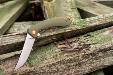 Knife in a bent position on wooden boards. Unusual shape of a knife.