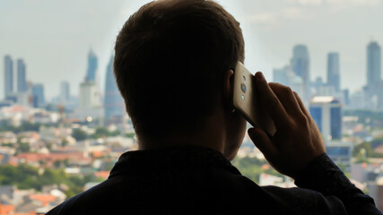 Man is talking on the phone in the background of the city.