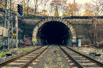 Fototapeta na wymiar Old stony tunnel with graffiti paintings, double-track railway and traffic lights