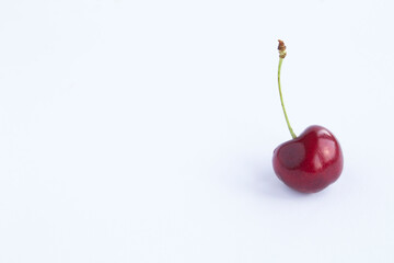 One red cherry on the white background. Closeup. Copy space.