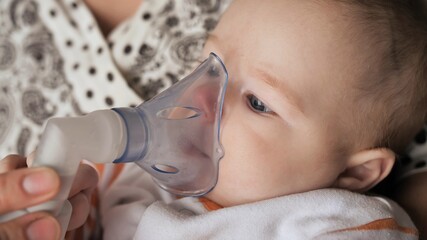 Funny one year old baby breathes with an inhaler.