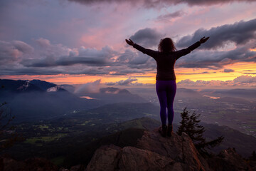Adventurous Girl on top of a Rocky Mountain overlooking the beautiful Canadian Nature Landscape during a dramatic Sunset. Taken in Chilliwack, East of Vancouver, British Columbia, Canada.