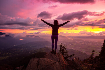 Adventurous Girl on top of a Rocky Mountain overlooking the beautiful Canadian Nature Landscape during a dramatic Sunset. Taken in Chilliwack, East of Vancouver, British Columbia, Canada.