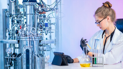 Fermentation processes in the laboratory. Laboratory bioreactor and chemist with test tubes and an...