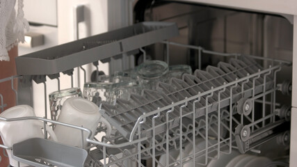 Close up open dishwasher with clean cups. Dishwasher at home kitchen. Cleaning chores concept.