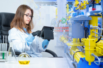 Laboratory of a chemical enterprise.A girl is sitting at a table with laboratory utensils against...