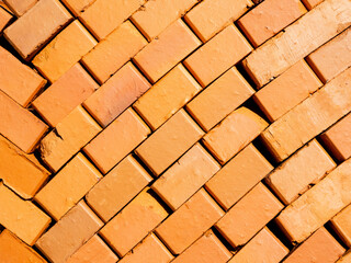 The bright orange bricks are neatly stacked. Red brick texture. Construction background or screensaver. Sale or storage of construction materials