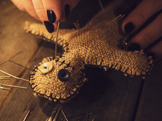 A sorceress pierces a voodoo doll with a pin, causing harm or damage to a person, close-up....