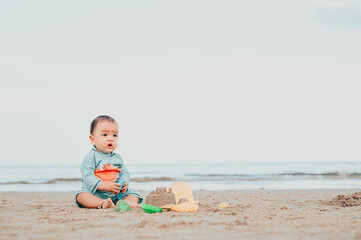 kid playing with sand on the beach by the sea. holidays with children near the ocean