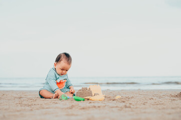 kid playing with sand on the beach by the sea. holidays with children near the ocean