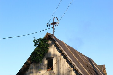 the roof of an old house with power wires on blue sky and grass