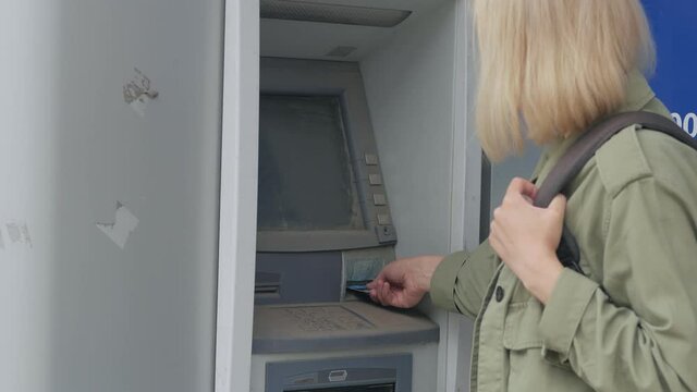 The woman unsuccessfully enters the pin code into the damaged ATM.