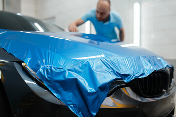 Car wrapping, man installs protective vinyl foil