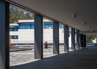 Una mujer atravesando un patio en un edificio de oficinas con columnas