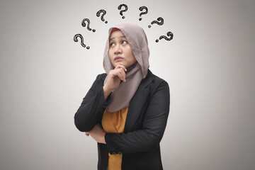 Beautiful Asian muslim business woman wearing hijab looking up and thinking with question mark, businesswoman confused of a problem