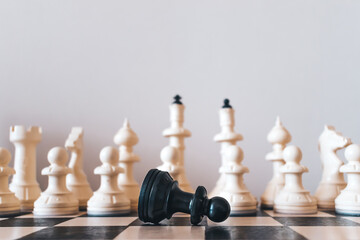 Defeated black chess pawn on a chessboard.Blurred white chess pieces in the background.Black Lives...