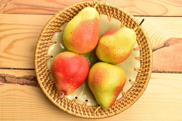 Organic juicy pears on a ceramic plate, close-up, on a wooden table.