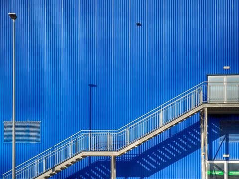 Escaleras metalicas en el exterior de un almacen de metal de color azul
