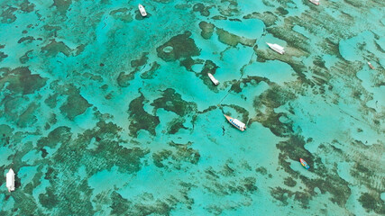 Sea reefs off the coast of the village of Lembongan with boats on the island of Nusa Lembongan. Indonesia. Aerial view.
