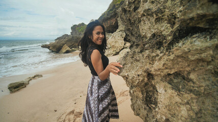 Fototapeta na wymiar Indonesian girl posing on a beautiful and rocky beach in Bali. Idonezia.