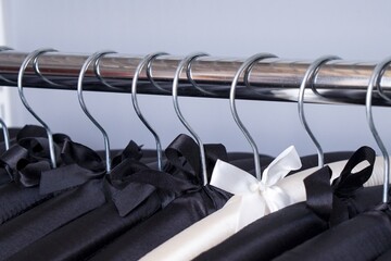 Row of black soft silk hangers with alone elegant white one between there. Luxury fashionable boutique concept. Perfection wardrobe. Individuality fashion concept.