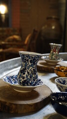 A porcelain tea glass on the wooden table. Tea in a porcelain glass cup on a wooden tray. A cup of traditional Turkish tea. Tea is a common drink in Turkish and Arabic culture. Low section of a glass.