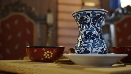 A porcelain tea glass on the table. Tea in a porcelain glass cup on a wooden tray. A cup of traditional Turkish tea. Tea is a common drink in Turkish and Arabic culture. Low section of a glass.