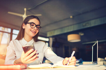 Cheerful young female freelancer felling happy to receive message from client suggesting working...