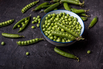 young  green peeled peas in a bowl on black background