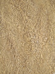 A beautiful multi-colored structure of sand, shells, pebbles, and seawater. Mediterranean beach, background, abstraction.