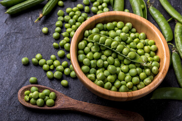 young  green peeled peas in a bowl on black background