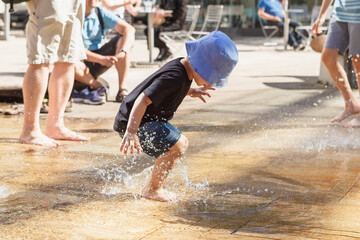 Little boy playing in fountain on a heat day