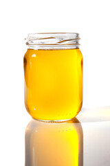 Glass jar with melted ghee butter over white background. Nutrition concept - Healthy food, Diet, Detox, Clean Eating or Vegetarian concept.