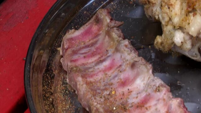 The cook sprinkles the ribs with spices. Meat preparation