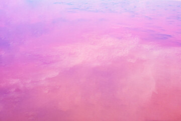  Pink background. Clouds are reflected in the pink lake. Copy space for text.