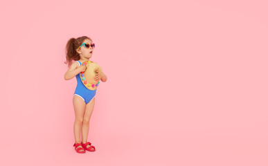 Little child girl in sunglasses in a bathing suit resting on a pink background. Summer rest concept