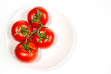 branch of red tomatoes on a white plate